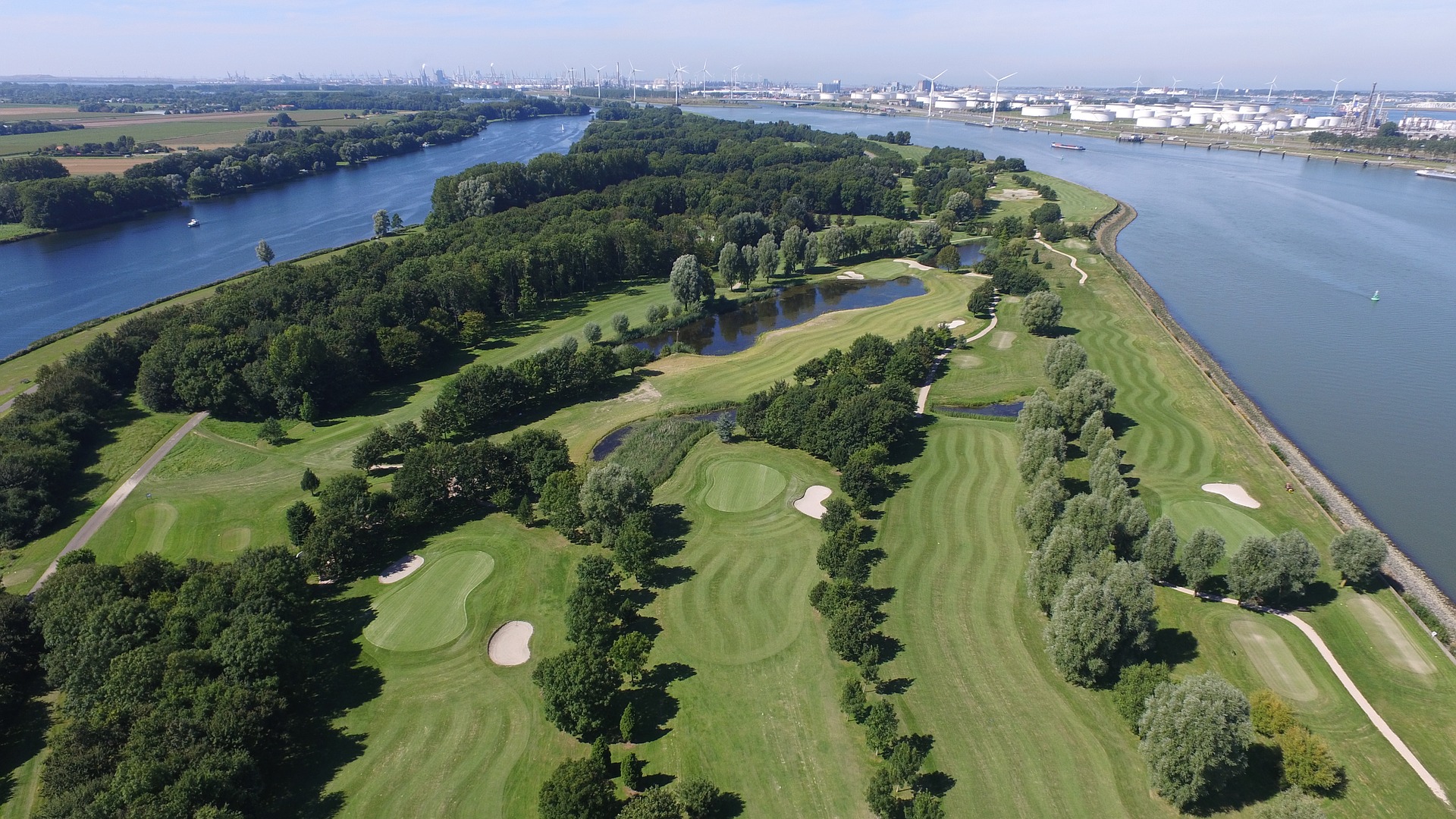 aerial shot of a golf course with a city on the horizon